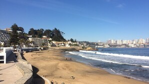 Una playa con un muro de piedra y el horizonte de una ciudad al fondo.