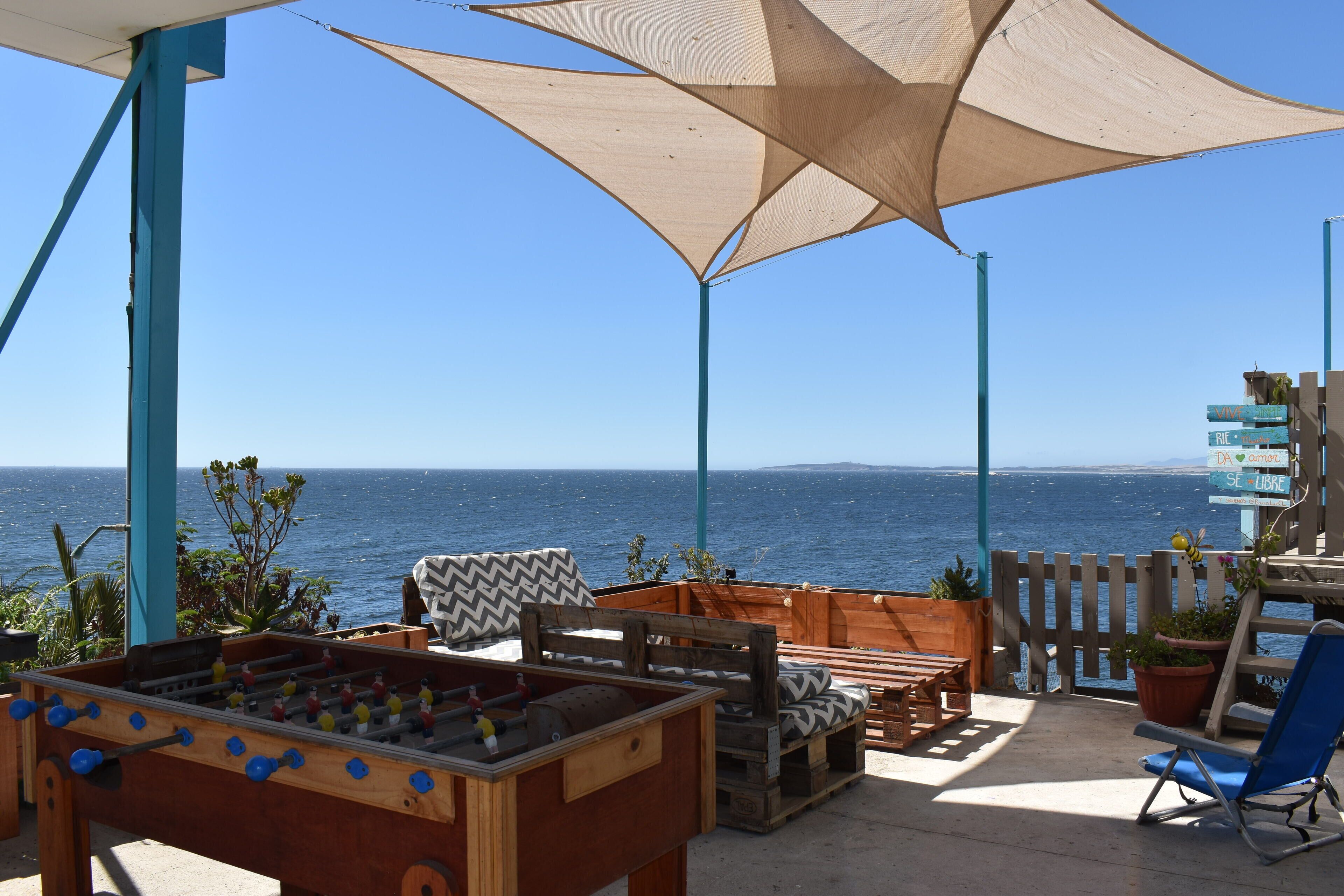 Una mesa de fútbol de madera, un sillón azul y vista al mar.