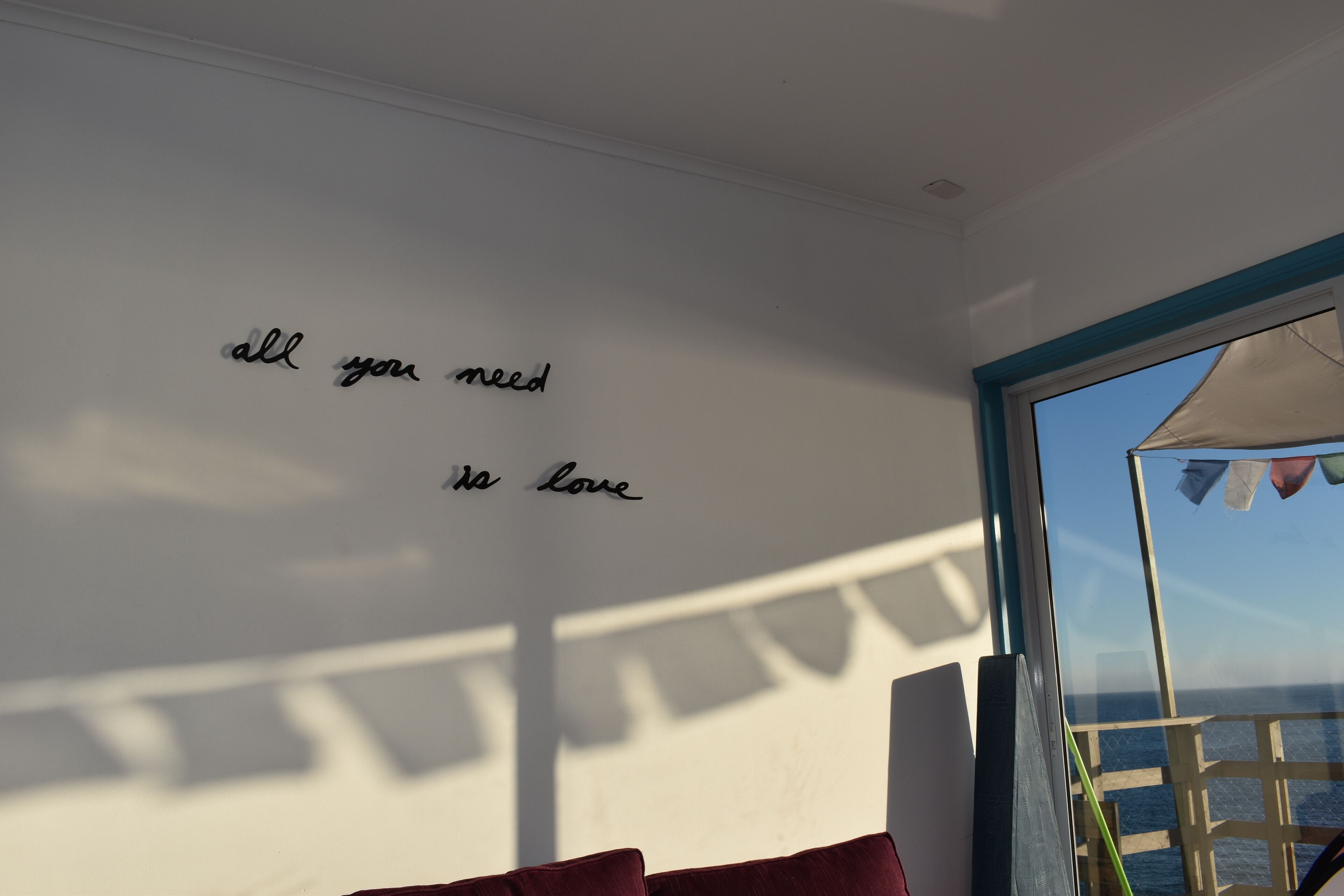 Um quarto com uma parede exibindo a frase 'all you need is love'.