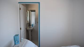 Ein Schlafzimmer mit einem Bett, einem kleinen Nachttisch und einem durchgegangenen Tür sichtbaren Badezimmer.