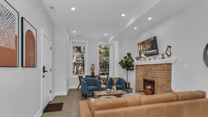 A living room with a fireplace, a sofa, and a dining area with chairs. - 3BD West Town Gem: Explore the Windy City in Style (Chicago)