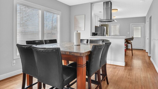 A dining area with a wooden table and black chairs, a kitchen in the background, and a hallway leading to another room. - SWEET HOUSTON 14 people, 4 Bethrooms, 2 Full Bath. Pool, Central Houston. (Houston)