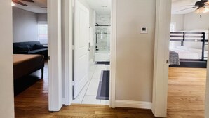 A hallway leading to a bathroom with a shower, a bedroom with a bunk bed, and a living area with a couch and a coffee table. - SWEET HOUSTON 14 people, 4 Bethrooms, 2 Full Bath. Pool, Central Houston. (Houston)