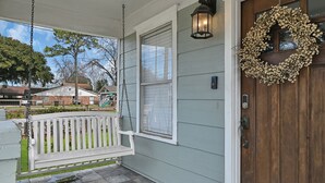 A porch with a white swing, a wooden door with a wreath, and a window with blinds. - SWEET HOUSTON 14 people, 4 Bethrooms, 2 Full Bath. Pool, Central Houston. (Houston)
