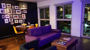 Un salon moderne avec un canapé violet, une table basse en bois et un coin repas comprenant une table et des chaises.