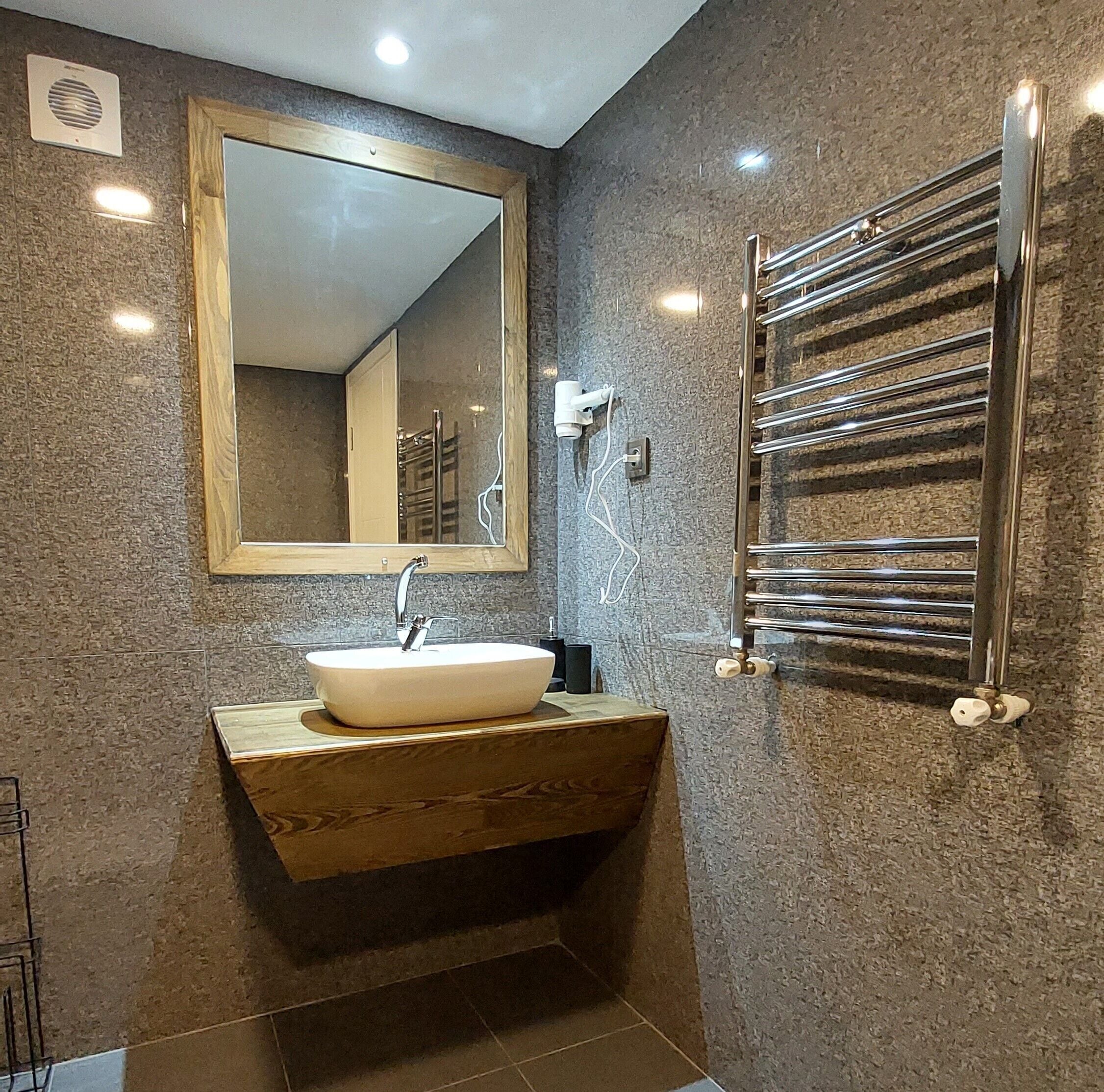 Un baño con un espejo grande, un lavabo y un toallero.