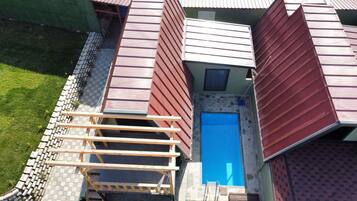 A residential building with a swimming pool, a wooden deck, and a stone wall.