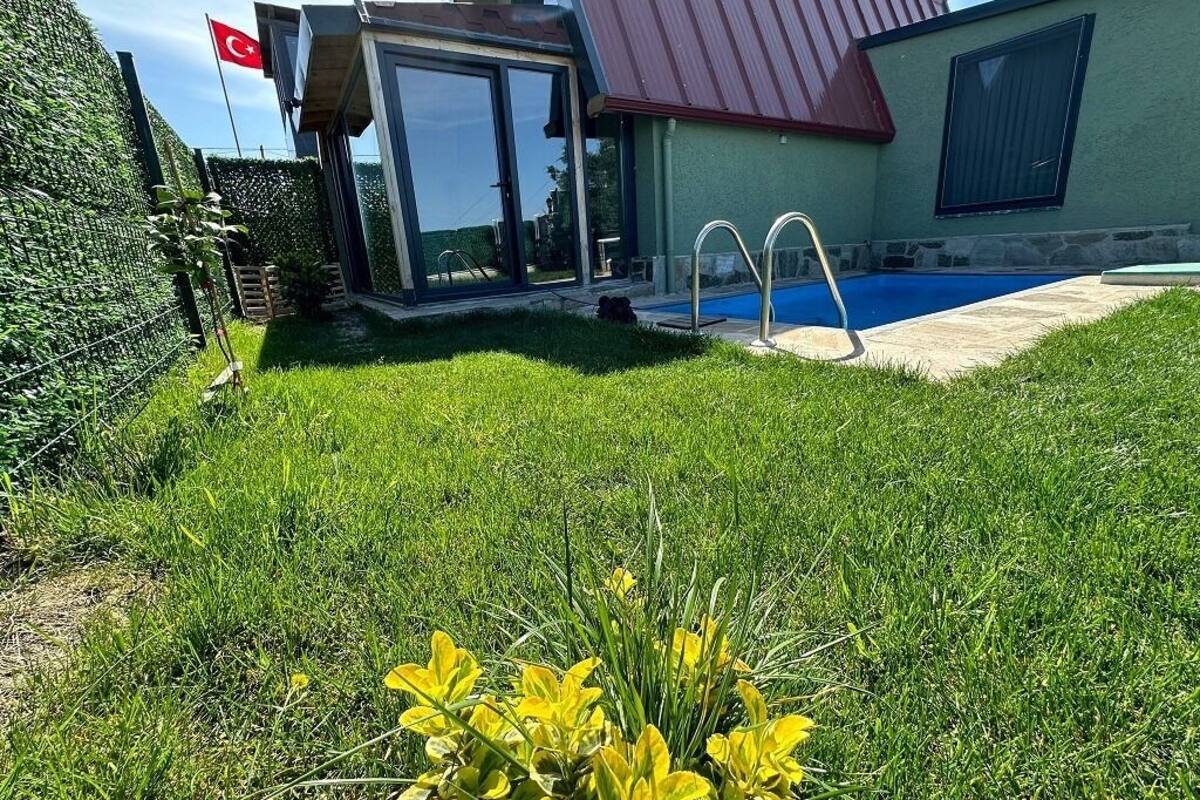 A residential property with a swimming pool, a glass-enclosed patio, and a flag.