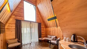 Ein gemütliches Holzhäuschen mit Schlafzimmer im oberen Bereich, Essbereich und Küchenzeile.