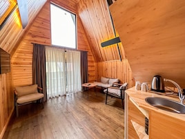 Una cabaña acogedora de madera con habitación en el altillo, comedor y kitchenette.