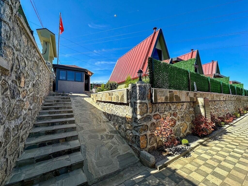 Escadaria de pedra que leva a um edifício com telhado vermelho, uma bandeira e um jardim bem cuidado.