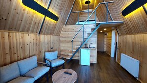 Ein gemütliches Interieur mit Holzausstattung, einer Couch, einem Couchtisch und einer Treppe, die in eine obere Ebene führt.