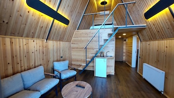 A cozy interior with a wooden interior, a sofa, a coffee table, and a staircase leading to an upper level.
