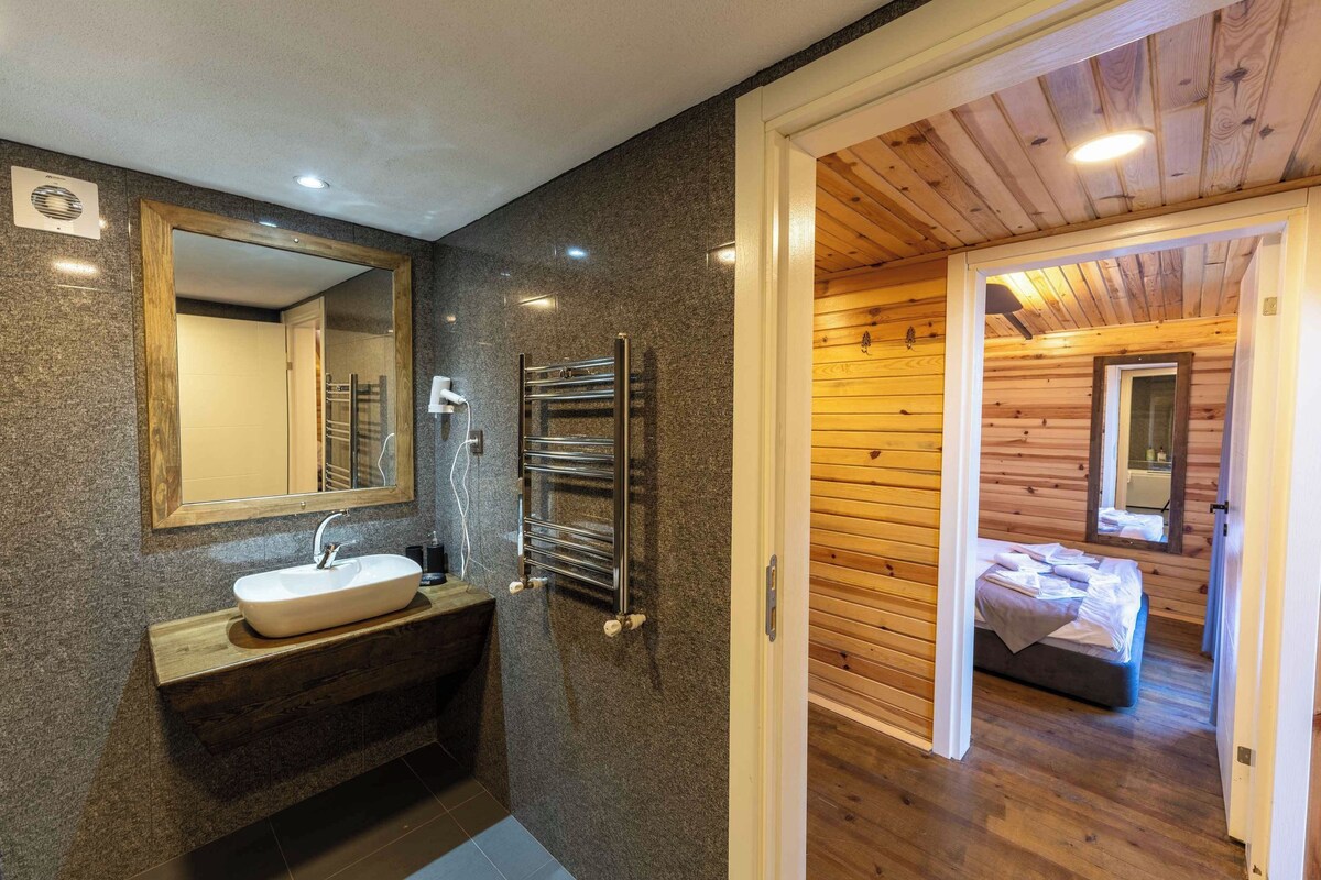 A modern bathroom with a granite countertop sink, a mirror, and a towel rack.
