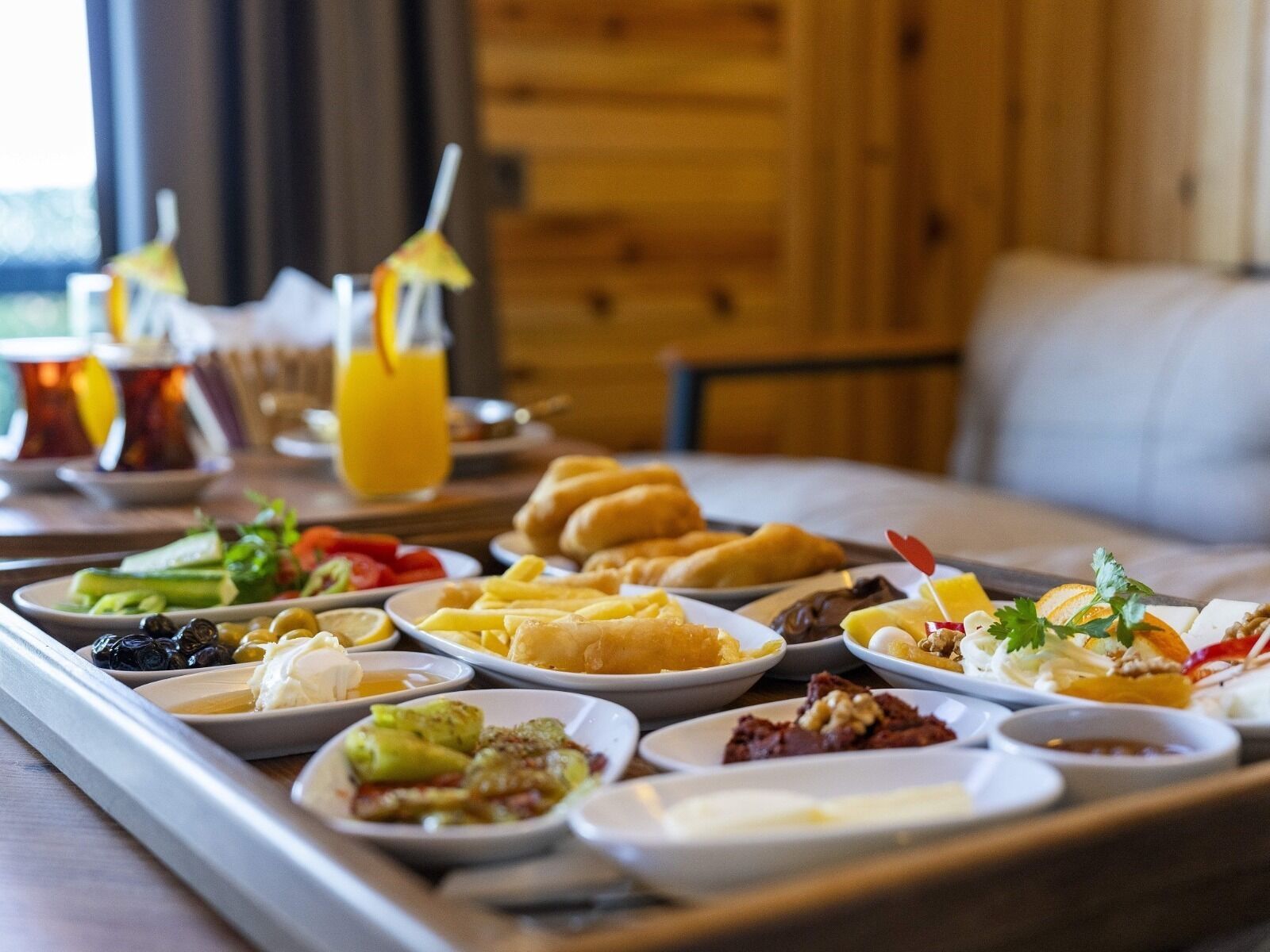 A breakfast buffet with various dishes, drinks, and a cozy wooden interior.