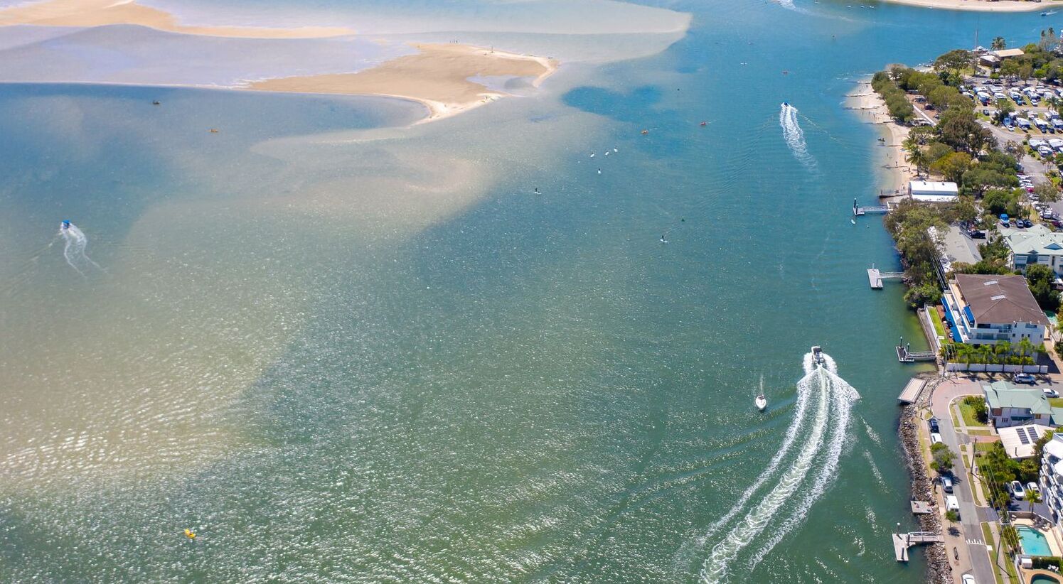 Vista aérea de una zona costera con un puerto deportivo, barcos y una playa.
