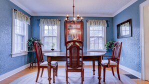 Une salle à manger avec une table et des chaises en bois, des murs bleus et un lustre.