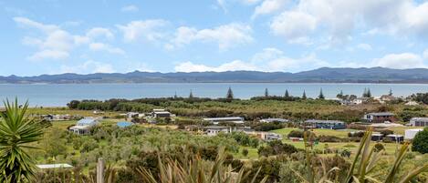 A coastal residential area with houses, a lake, and mountains in the background.