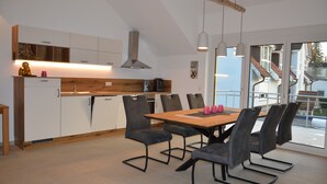 Una cocina moderna con armarios blancos, encimera de madera y una zona de comedor con mesa y sillas.