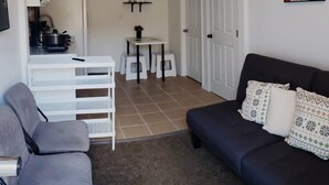 A compact living space with a sofa, a small dining table, and a kitchenette area. - Cozy Apartment in S Orlando, approx. 20 minutes away from Disney and Universal. (Orlando)