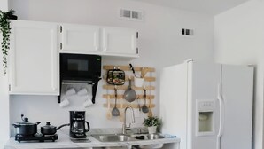 A compact kitchen with white cabinets, a microwave, a coffee maker, and a sink. - Cozy Apartment in S Orlando, approx. 20 minutes away from Disney and Universal. (Orlando)