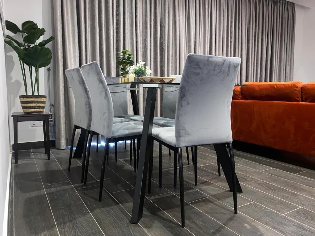 Un área de comedor con una mesa, sillas y una planta en maceta.