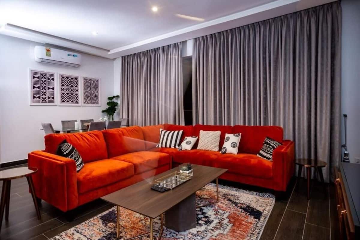 Una sala de estar moderna con un sofá seccional rojo, una mesa de centro de madera y cortinas estampadas.