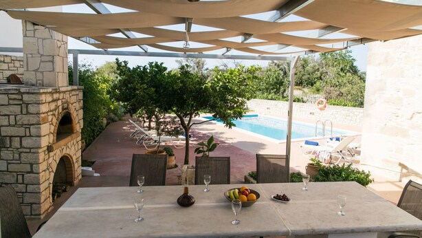 An outdoor dining area with a stone fireplace, a pool, and a view of the pool area. - Afroditi 4 bedrooms,pool,Picturesque village (Pigouniana)