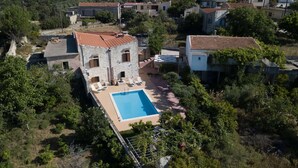 An aerial view of a property with a swimming pool, stone buildings, and surrounding greenery. - Afroditi 4 bedrooms,pool,Picturesque village (Pigouniana)