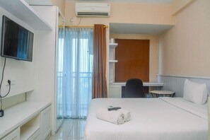 Habitación de hotel con cama, escritorio, silla, televisor montado en la pared y unidad de aire acondicionado.