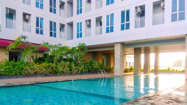 A swimming pool with clear blue water, surrounded by a tiled deck. - Minimalist And Comfy Studio At Grand Dhika City Apartment (Bekasi)