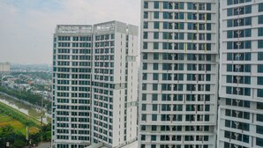 A modern high-rise building with multiple floors, large windows, and a flat facade. - Minimalist And Comfy Studio At Grand Dhika City Apartment (Bekasi)