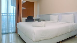 A hotel room with a large bed, a desk, and a chair. - Minimalist And Comfy Studio At Grand Dhika City Apartment (Bekasi)