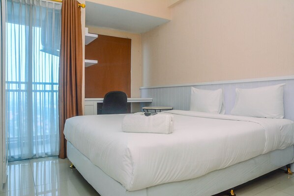 Una habitación de hotel con una cama grande, un escritorio y una silla.