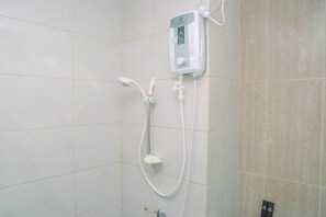 Un baño con cabina de ducha, cabezal de ducha manual y panel de control en la pared.