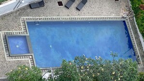 An aerial view of a rectangular swimming pool with a smaller square section on one side, surrounded by a tiled deck. - Good Deal And Cozy Stay Studio Room Tifolia Apartment (Jakarta)