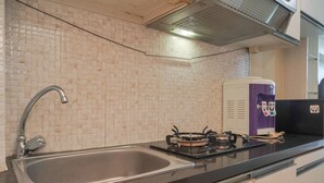 A kitchen with a stainless steel sink, a gas stove, and a water dispenser. - Good Deal And Cozy Stay Studio Room Tifolia Apartment (Jakarta)