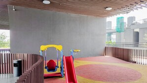 A playground area with a red slide, a climbing structure, and a rubberized floor.