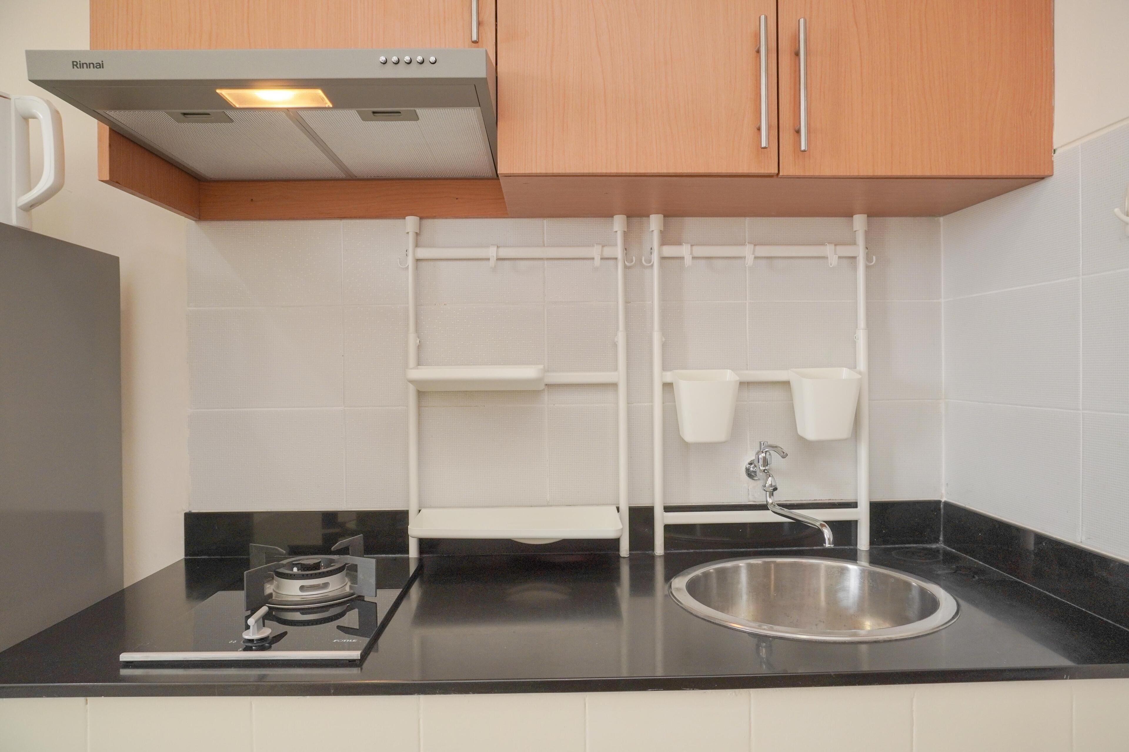 A modern kitchen with a gas stove, stainless steel sink, white cabinets, and a black countertop.