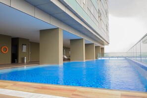 Une piscine intérieure à l’eau d’un bleu cristallin, entourée de murs de couleur beige et dotée d’un sol carrelé.