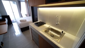 A modern kitchen with a built-in sink, a countertop, and a small electronic device. - Tidy And Cozy Stay Studio Apartment At Suncity Residence (Sidoarjo)