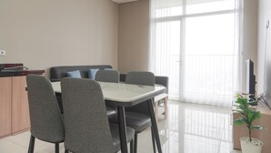 A modern living room with a dining area, large windows, and a flat-screen TV.