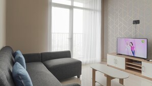 A modern living room with a grey sofa, a small white table, and a TV on a wooden stand.