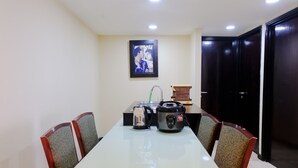 A dining area with a table, chairs, a kettle, a slow cooker, and a framed picture on the wall. - Strategic And Comfortable 2Br At Braga City Walk Apertment (Bandung)