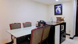 A dining area with a table and four chairs, a kitchen area with a kettle, a microwave, and a small refrigerator. - Strategic And Comfortable 2Br At Braga City Walk Apertment (Bandung)