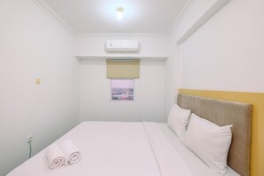 A hotel room with a bed, white linens, a window with a view, an air conditioner, and a small window with a view.