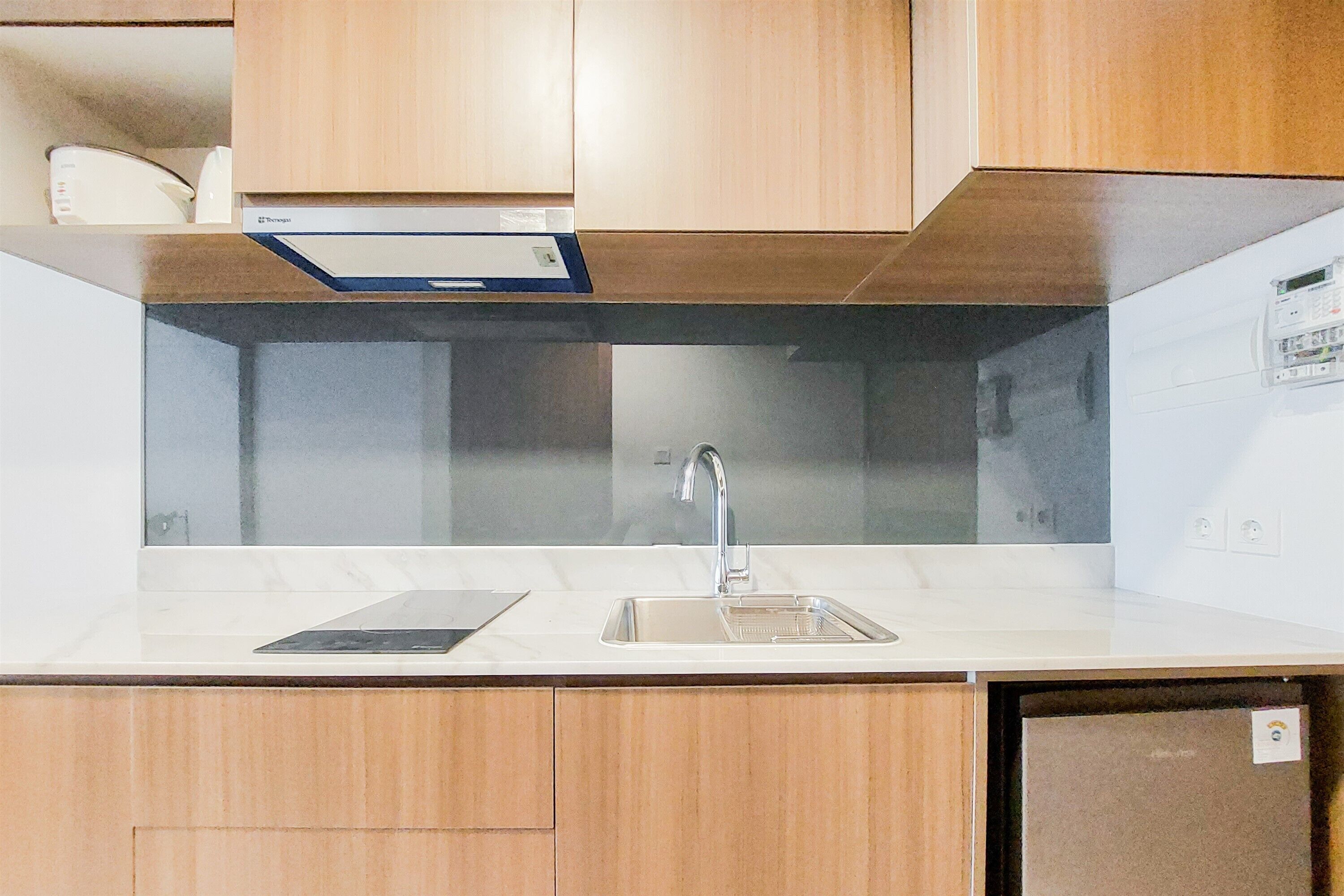 A modern kitchen with wooden cabinets, a stainless steel sink, and a built-in oven.