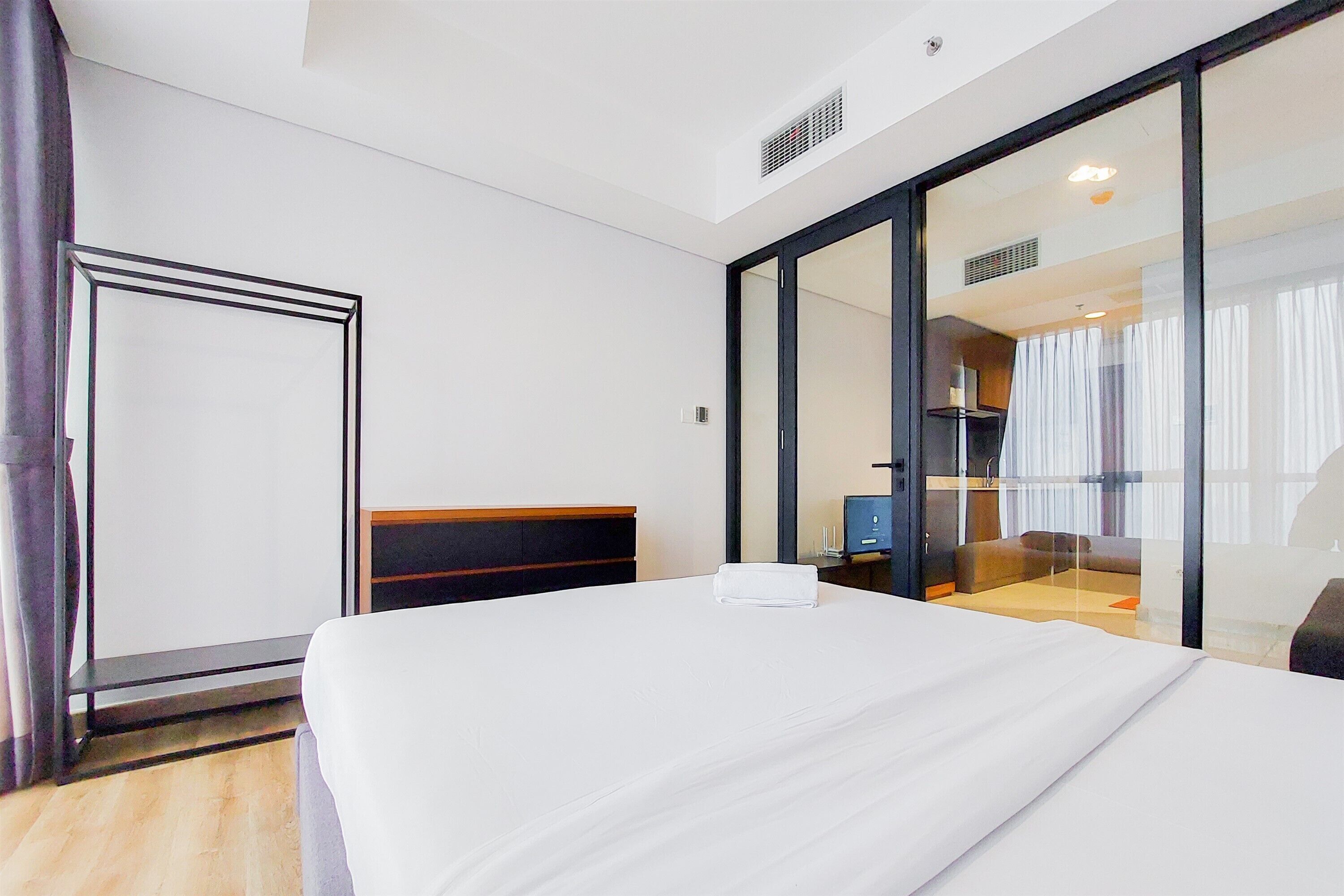 Une chambre d’hôtel moderne dotée d’un grand lit, d’un bureau et d’une cloison en verre.