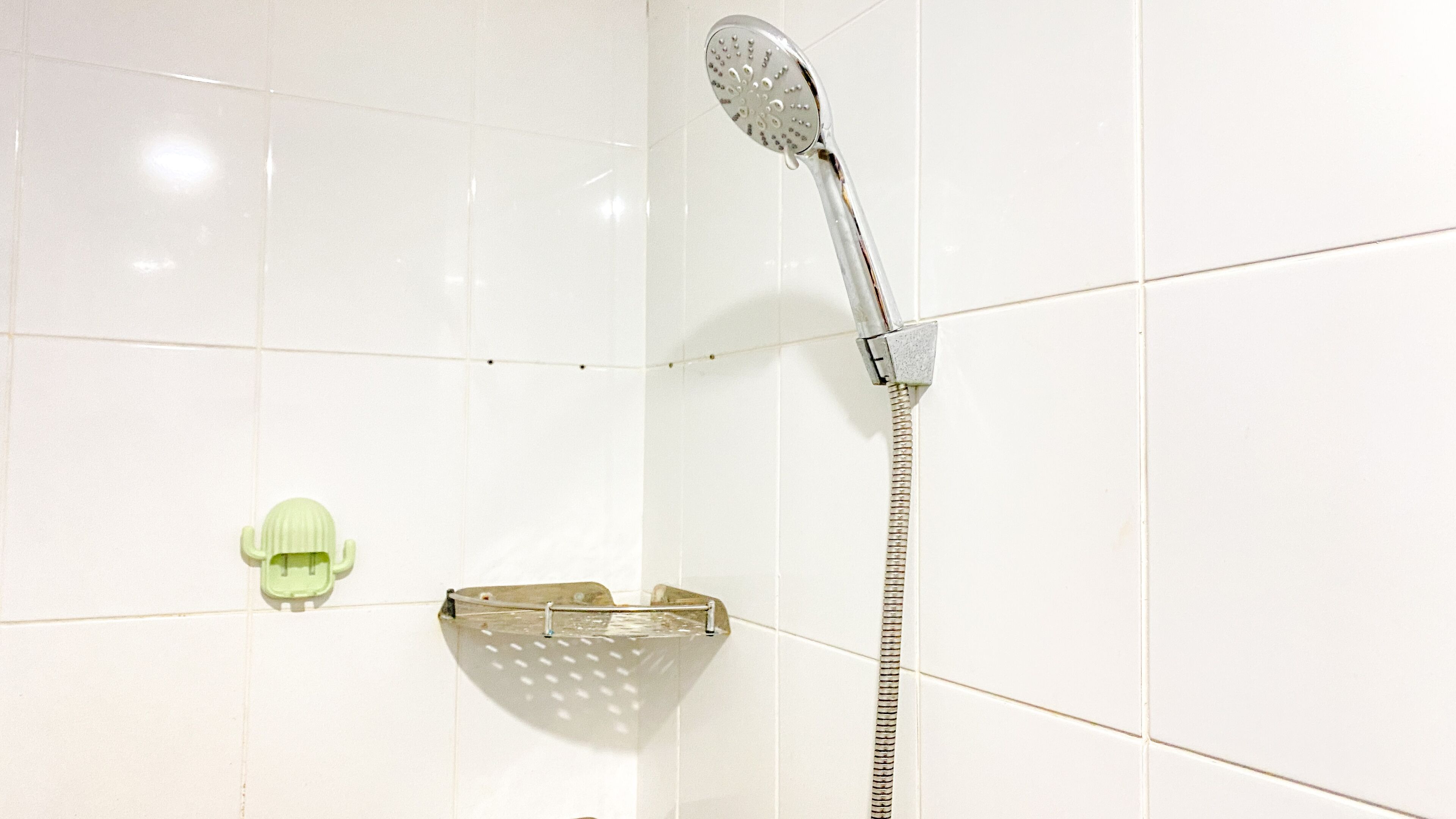 A shower with a handheld showerhead and a wall-mounted faucet.