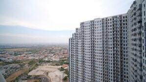 A high-rise building with multiple balconies and a view of a cityscape with residential areas and roads. - Compact And Homey 2Br At Benson Supermall Mansion Apartment (Surabaya)